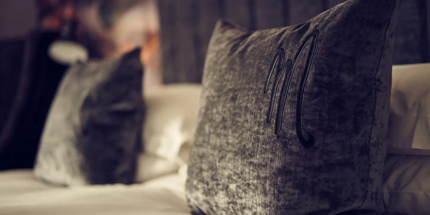 Close up of grey velvet pillow on bed.