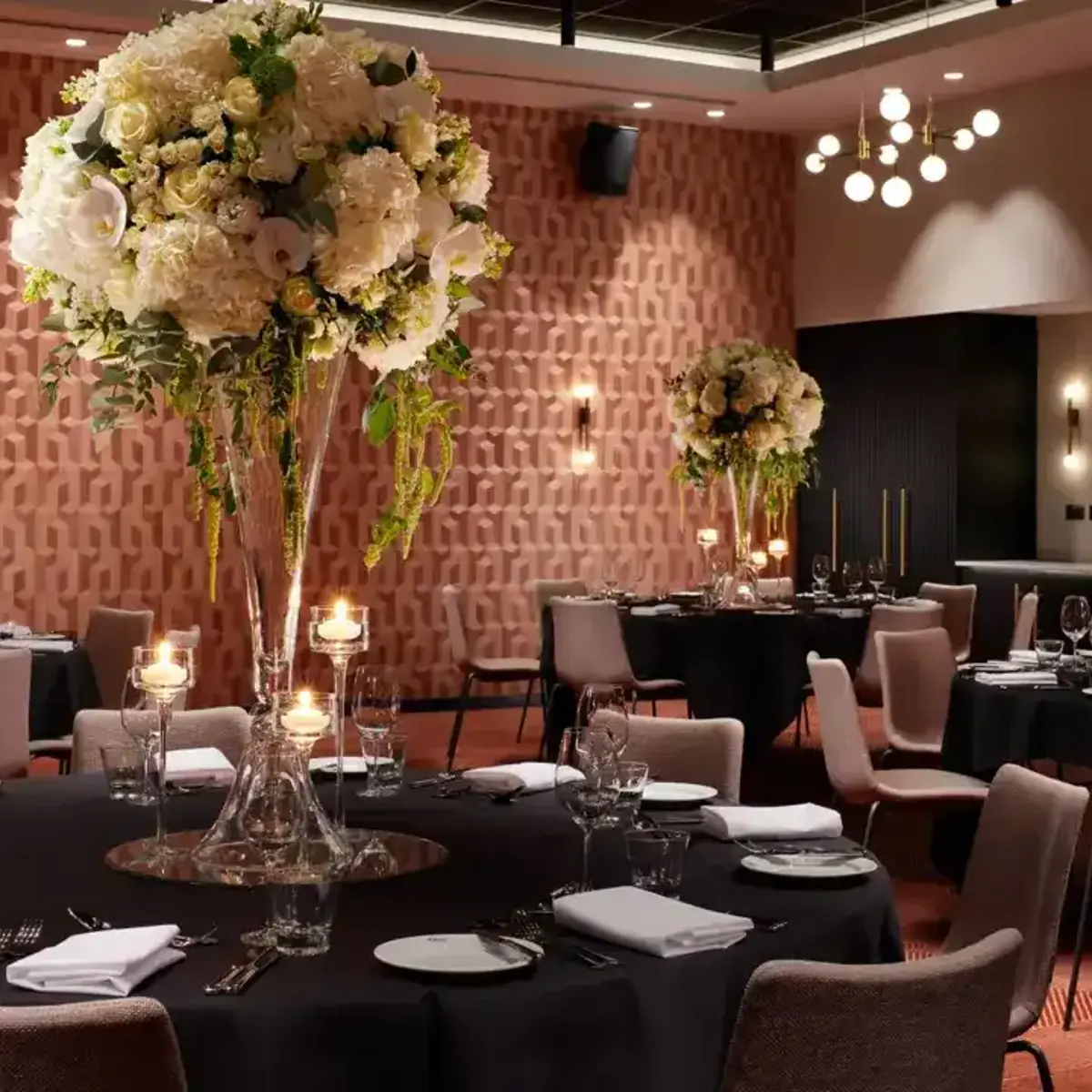 A dining room featuring tables, chairs, and vases filled with flowers.