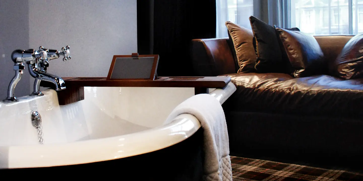 Bathroom with a bathtub placed beside a leather couch.
