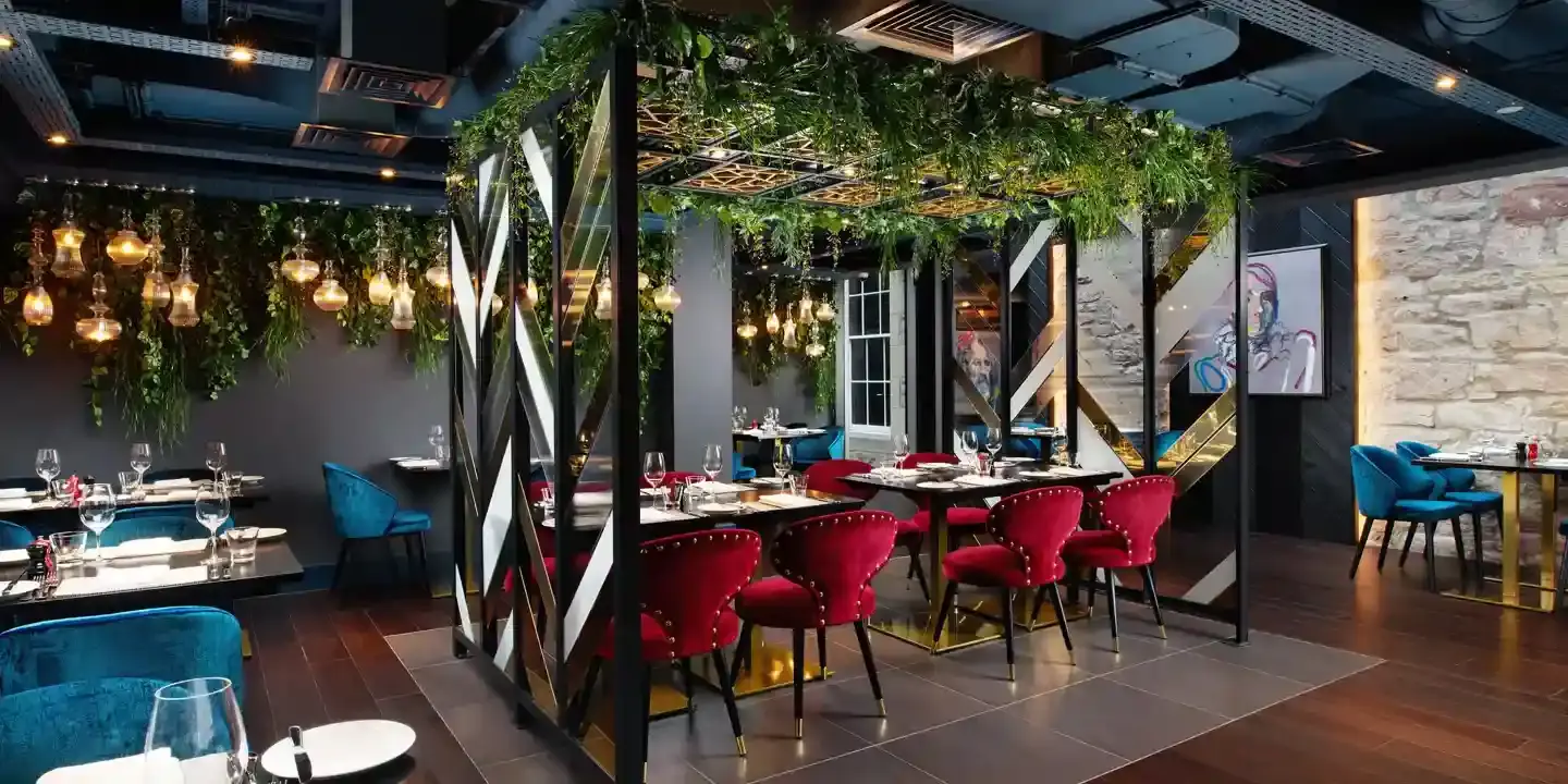 An image of a restaurant featuring a lengthy table adorned with red chairs.