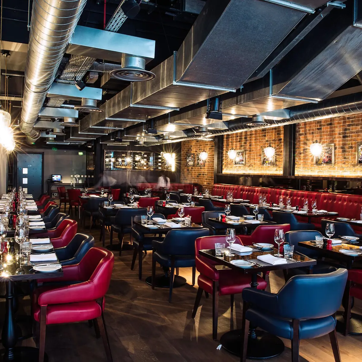 An image of a restaurant featuring a lengthy table adorned with red chairs.