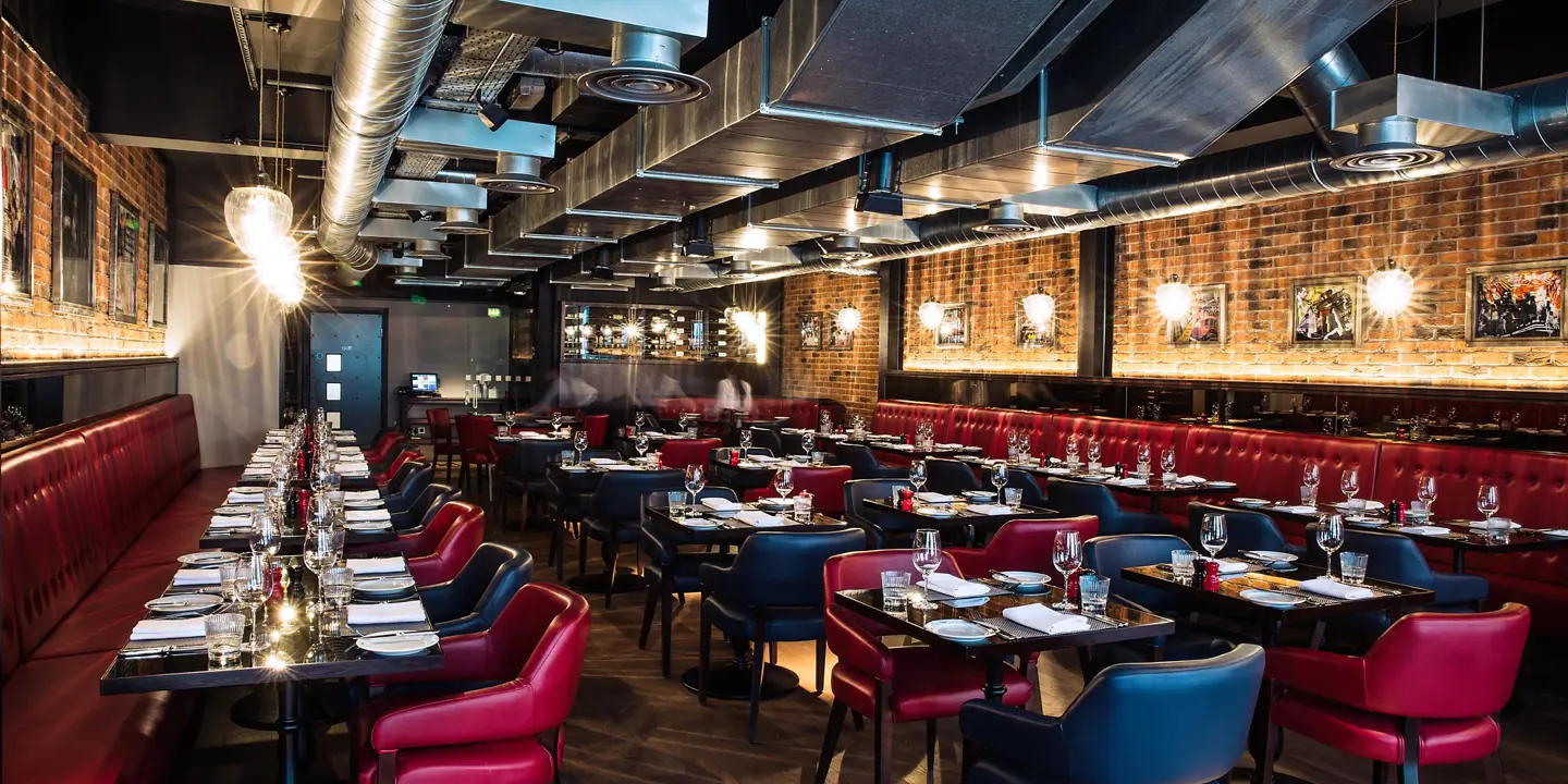 An image of a restaurant featuring a lengthy table adorned with red chairs.