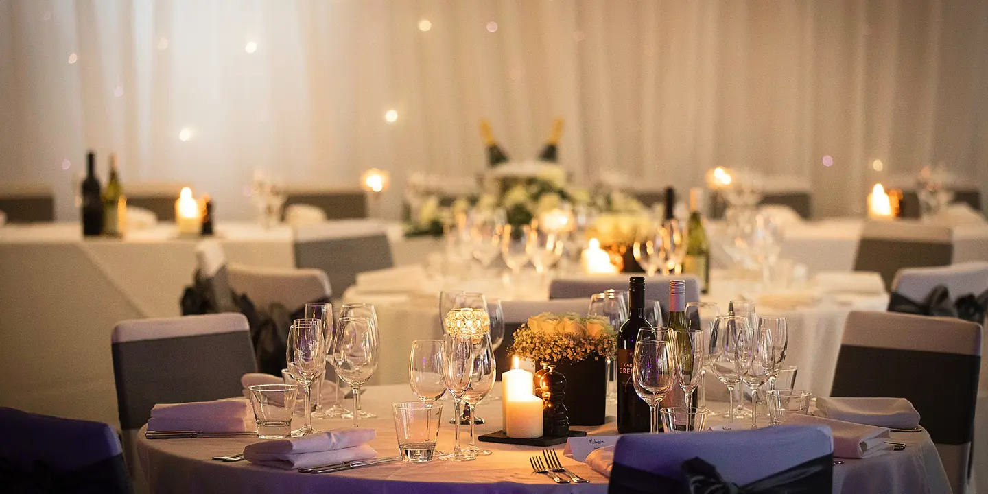 Table set for a wedding reception, adorned with elegant candles and beautiful flowers.
