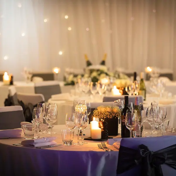 Table set for a wedding reception, adorned with elegant candles and beautiful flowers.