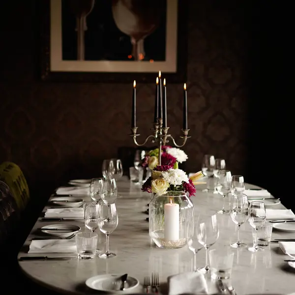 A table arranged for a formal dinner in a dimly lit room.