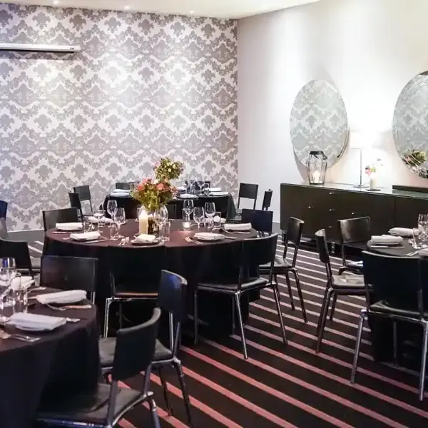 A dining room set with tables and chairs arranged for a dinner gathering.