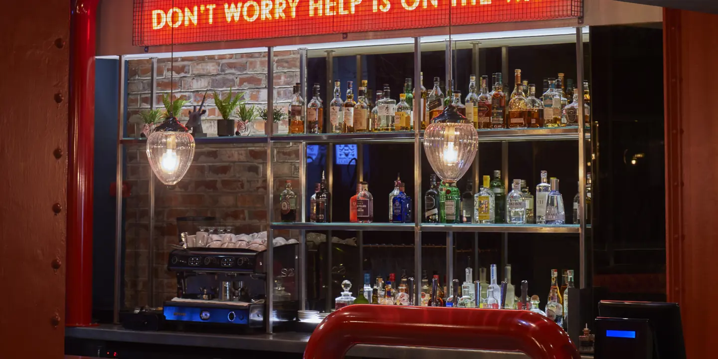 A bar with a neon sign displaying the message 'Don't worry help is on the way'.