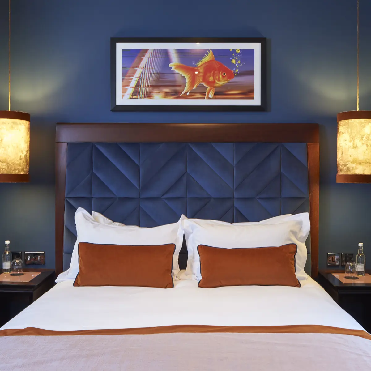 A bed featuring a stylish blue headboard adorned with vibrant orange pillows.