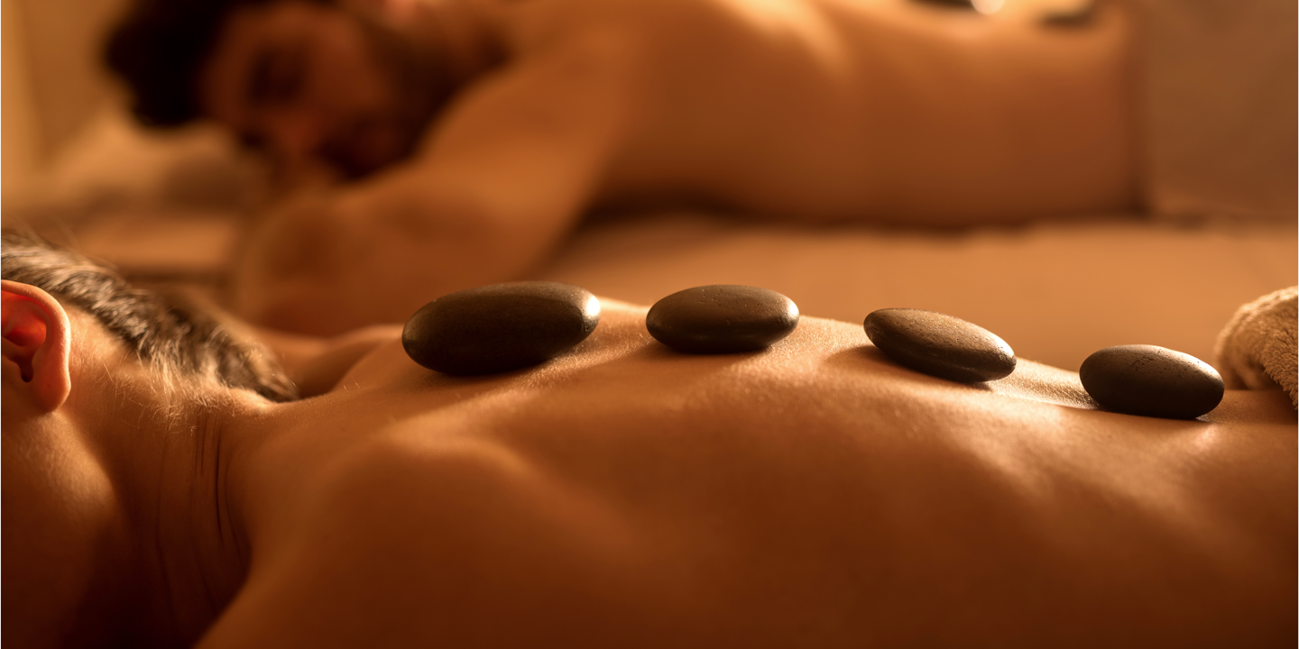A woman lying on a bed with heated stones placed on her back.