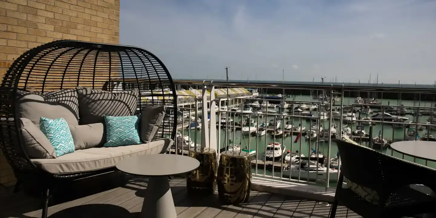 Balcony view of a harbor with a table and chairs.