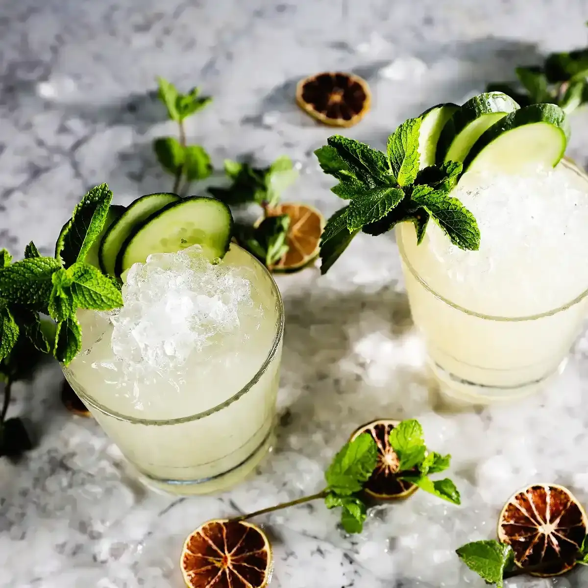 Two cocktail glasses filled with beverages and garnished.