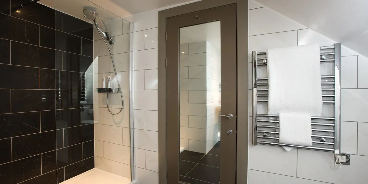 A bathroom featuring a walk-in shower with a mirror on the back of bathroom door.