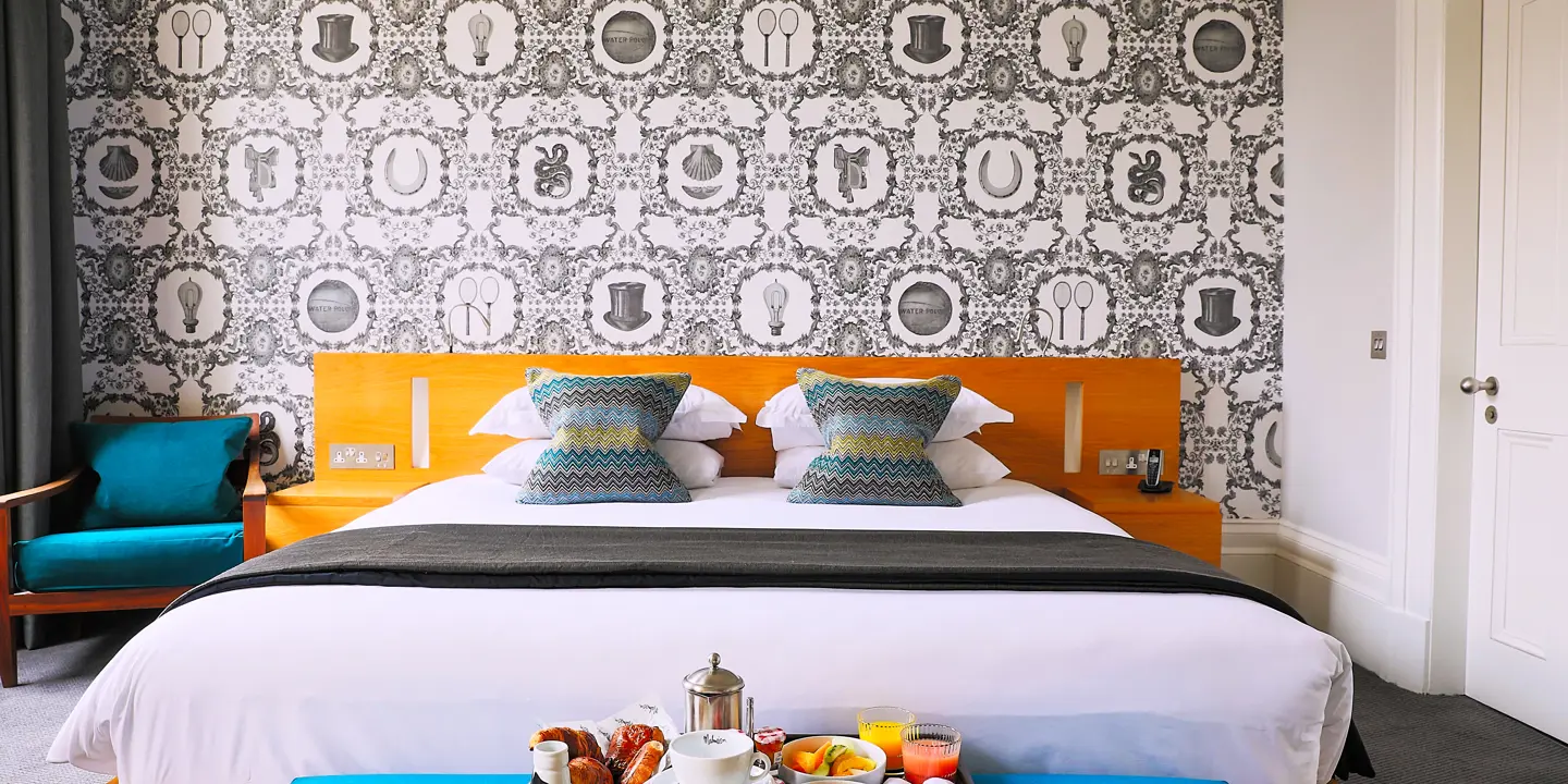 Brightly decorated room with a tray of fresh fruit at the end of the bed.
