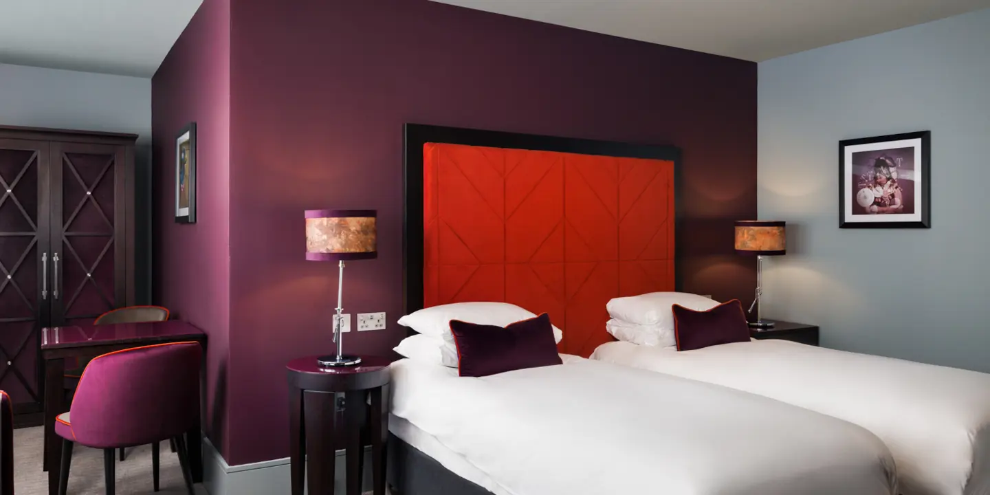 An elegantly furnished hotel room featuring a comfortable bed, spacious desk, chair and modern television.