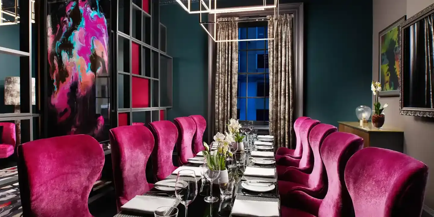 A dining room featuring a lengthy table adorned with pink chairs.