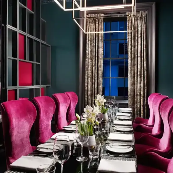 A dining room featuring a lengthy table adorned with pink chairs.