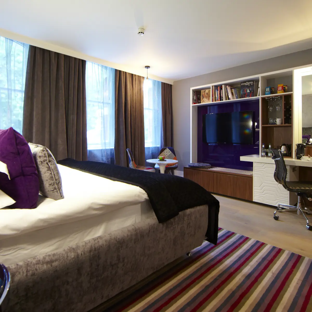 A well-arranged bedroom featuring a neatly made bed and a television.