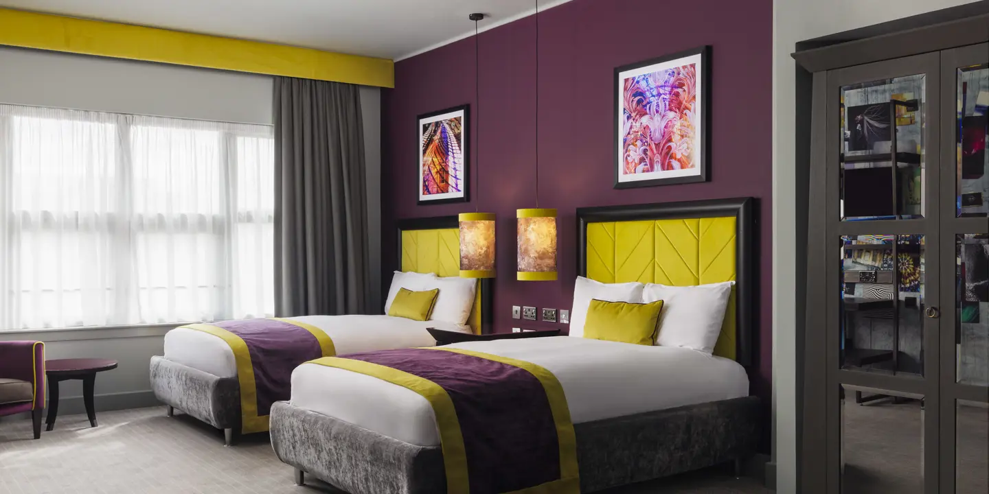 A spacious room with two double beds and a stylish chair.