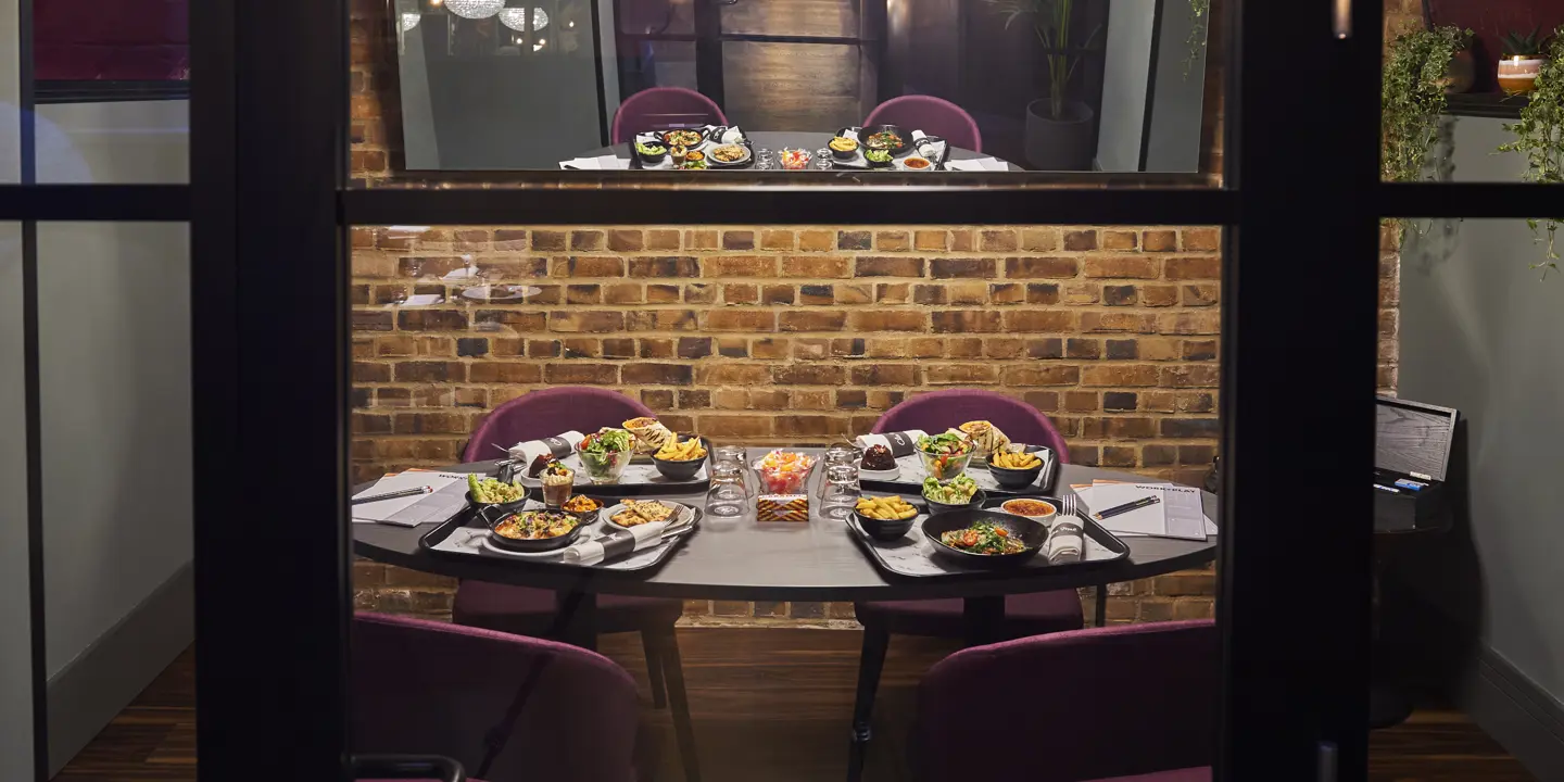 Plates of food arranged on a table in front of a brick wall.