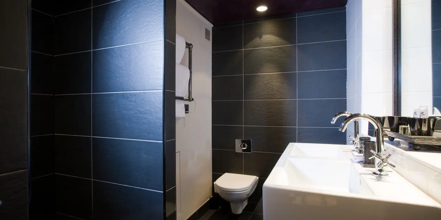 Bathroom featuring a toilet, sink, and shower stall.