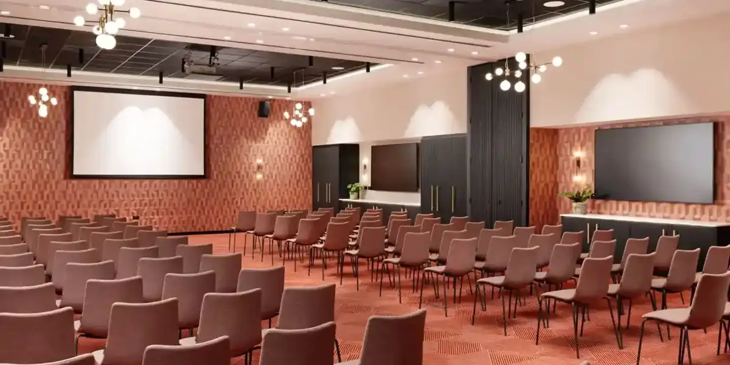 Conference room with neatly arranged rows of chairs and a large projector screen.
