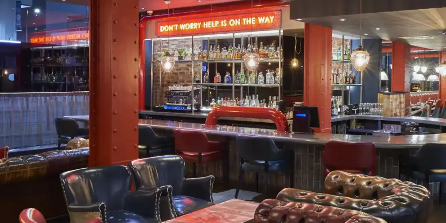 A bar with a neon sign displaying the message 'Don't worry help is on the way'.